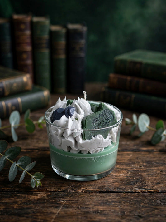 ALT: Vela aromática Slytherin 190g eucalipto vista superior detalle frosting blanco con figura verde y corazón azul sobre mesa madera con eucalipto
Nombre archivo: vela-eucalipto-slytherin-190g-detalle-frosting-topping.jpg