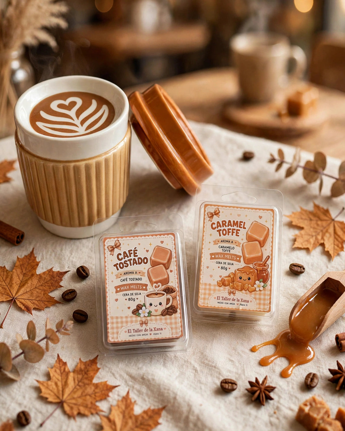 Pack Latte Cozy con quemador cerámico en forma de vaso de café latte con latte art y dos tabletas de wax melts de 80g de Caramel Toffee y Café Tostado de El Taller de la Xana sobre mesa otoñal con hojas y caramelo derretido